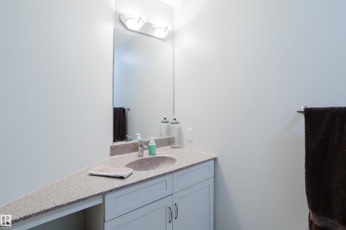 Bathroom vanity with an integrated sink, granite countertop, and light-colored cabinetry - 206 10108 125 Street, Edmonton, AB - Indoor Photo Showing Bathroom