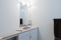 Bathroom vanity with an integrated sink, granite countertop, and light-colored cabinetry - 