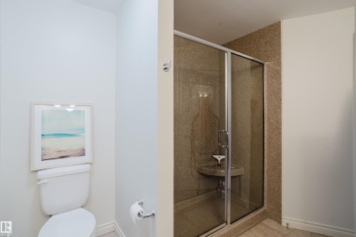 Bathroom featuring a glass-enclosed shower with a built-in corner bench and a toilet - 206 10108 125 Street, Edmonton, AB - Indoor Photo Showing Bathroom