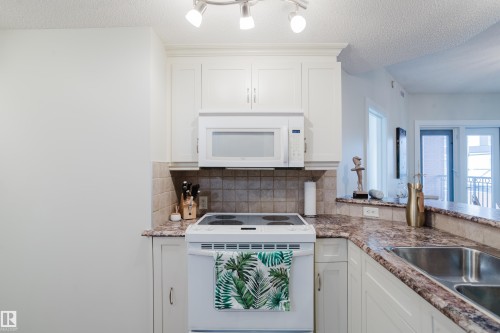 Kitchen featuring white cabinetry, a built-in microwave, an electric range, and a double basin sink - 206 10108 125 Street, Edmonton, AB - Indoor Photo Showing Kitchen With Double Sink