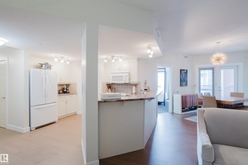 The kitchen features white cabinetry, a white refrigerator, and a white microwave - 206 10108 125 Street, Edmonton, AB - Indoor