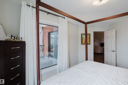 Bedroom featuring light-colored walls and a door leading to an outdoor balcony with a brick exterior - 206 10108 125 Street, Edmonton, AB - Indoor Photo Showing Bedroom