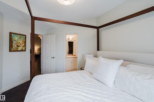 This bedroom features light-colored walls and dark flooring - 206 10108 125 Street, Edmonton, AB - Indoor Photo Showing Bedroom