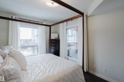 This bedroom features two windows, one of which includes a balcony view, and a ceiling light fixture - 
