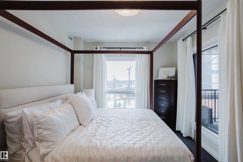 This room features expansive windows with white curtains, allowing for ample natural light - 206 10108 125 Street, Edmonton, AB - Indoor Photo Showing Bedroom