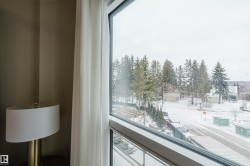 Expansive window offering views of the surrounding natural landscape, including mature trees and a snow-covered street - 