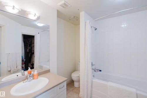 The property features a bathroom with a vanity, an integrated sink, and a mirror with overhead lighting - 206 10108 125 Street, Edmonton, AB - Indoor Photo Showing Bathroom