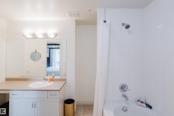 The bathroom features a vanity with an integrated sink, a large mirror, and a three-light fixture - 