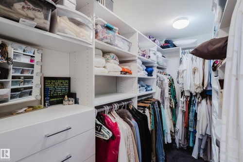 The property includes a walk-in wardrobe featuring extensive white built-in shelving, integrated drawers with metal pull handles, and a ceiling-mounted light fixture - 206 10108 125 Street, Edmonton, AB - Indoor With Storage