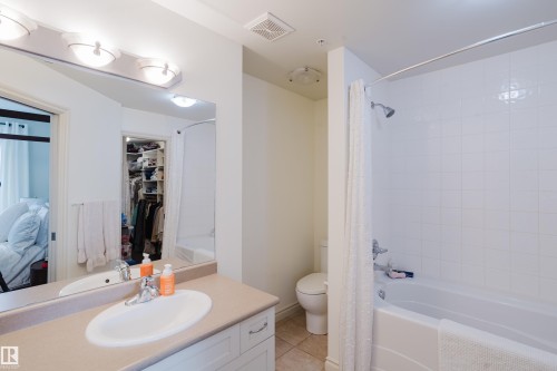 Bathroom featuring a vanity with a countertop and undermount sink, a bathtub with shower, and tiled flooring - 206 10108 125 Street, Edmonton, AB - Indoor Photo Showing Bathroom
