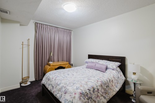 Bedroom with light-colored walls, dark flooring, and window treatments - 206 10108 125 Street, Edmonton, AB - Indoor Photo Showing Bedroom