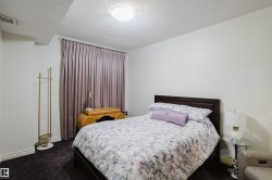 Bedroom with light-colored walls, dark flooring, and window treatments - 