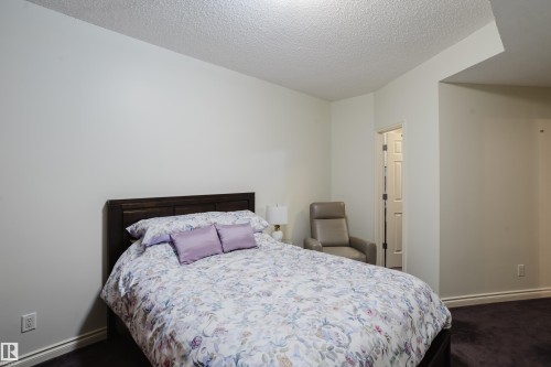 This room features a dark wood bed frame, light-colored walls, and dark carpeting - 206 10108 125 Street, Edmonton, AB - Indoor Photo Showing Bedroom