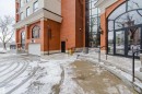 The property features a brick exterior with arched windows, a large glass entrance, and a garage door - 206 10108 125 Street, Edmonton, AB  - Outdoor 