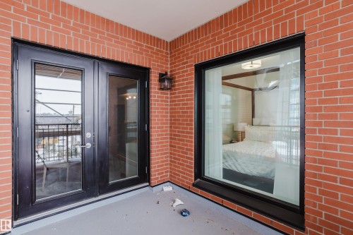 The property features a private balcony with red brick walls and a black exterior light fixture - 206 10108 125 Street, Edmonton, AB - Outdoor With Exterior