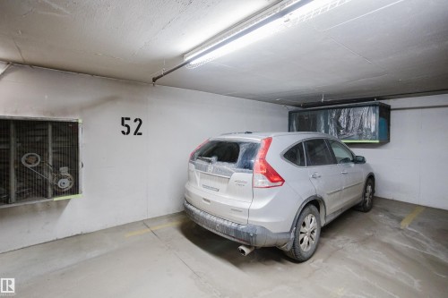 Dedicated parking space within a well-lit garage, featuring concrete flooring and a clearly marked stall number - 206 10108 125 Street, Edmonton, AB - Indoor Photo Showing Garage