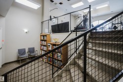 This property features a carpeted staircase with a metal railing and a wall-mounted light fixture - 