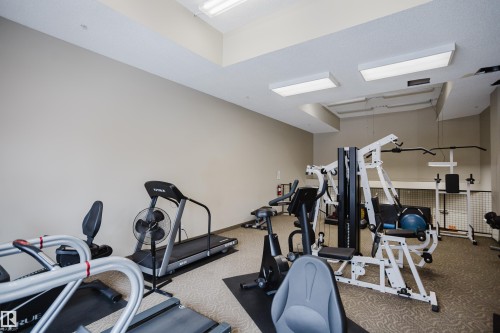 The property features a dedicated fitness area with various exercise equipment, including treadmills, stationary bikes, and a multi-station weight machine - 206 10108 125 Street, Edmonton, AB - Indoor Photo Showing Gym Room