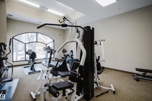 The property features a dedicated fitness area with various exercise machines, including cardio and strength training equipment - 206 10108 125 Street, Edmonton, AB - Indoor Photo Showing Gym Room