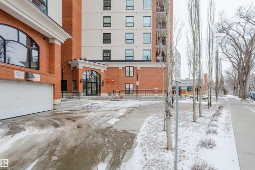 The property features a brick exterior with large arched windows and a white garage door - 206 10108 125 Street, Edmonton, AB - Outdoor