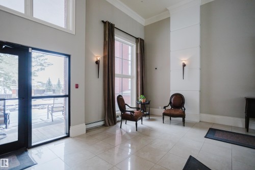 This space features high ceilings, large windows with full-length drapes, and elegant wall sconces - 206 10108 125 Street, Edmonton, AB - Indoor Photo Showing Other Room