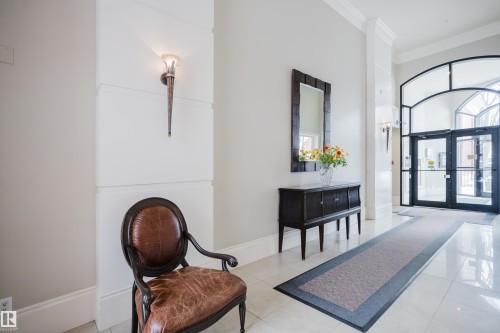 Entryway featuring light-colored flooring, a decorative wall sconce, and an arched glass door - 206 10108 125 Street, Edmonton, AB - Indoor Photo Showing Other Room