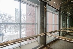The property offers a modern elevator with clear glass panels, providing views of the surrounding neighborhood and a nearby brick building - 