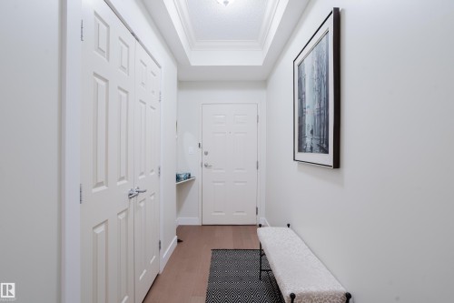 Entryway featuring light-colored hardwood flooring, a white paneled door, and a coffered ceiling - 206 10108 125 Street, Edmonton, AB - Indoor Photo Showing Other Room