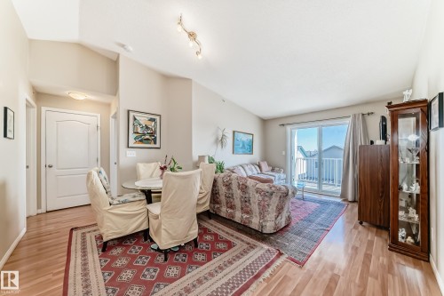 The living area features light wood flooring, a vaulted ceiling, and sliding glass doors leading to a balcony - 324 9525 162 Avenue Nw, Edmonton, AB - Indoor