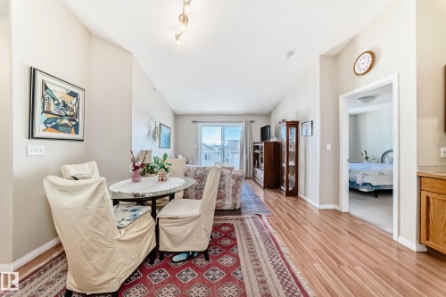 This inviting interior features a dining area with a round table and chairs, hardwood flooring throughout, and light-colored walls - 324 9525 162 Avenue Nw, Edmonton, AB - Indoor Photo Showing Dining Room