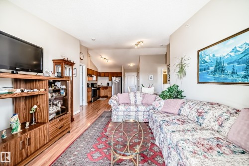 The living area features hardwood flooring, vaulted ceilings, and a decorative area rug - 324 9525 162 Avenue Nw, Edmonton, AB - Indoor Photo Showing Living Room
