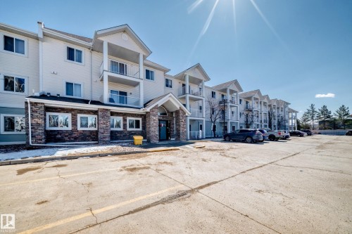 The property features an exterior with white siding and stone accents, along with several balconies - 324 9525 162 Avenue Nw, Edmonton, AB - Outdoor With Facade