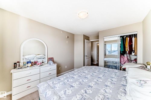 This room features neutral-toned walls, a ceiling light fixture, and a mirrored sliding closet door - 324 9525 162 Avenue Nw, Edmonton, AB - Indoor Photo Showing Bedroom