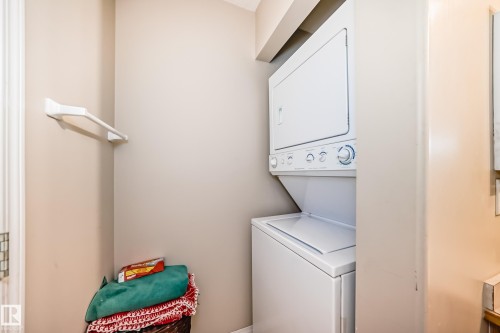 Dedicated laundry area featuring a white stacked washer and dryer unit - 324 9525 162 Avenue Nw, Edmonton, AB - Indoor Photo Showing Laundry Room