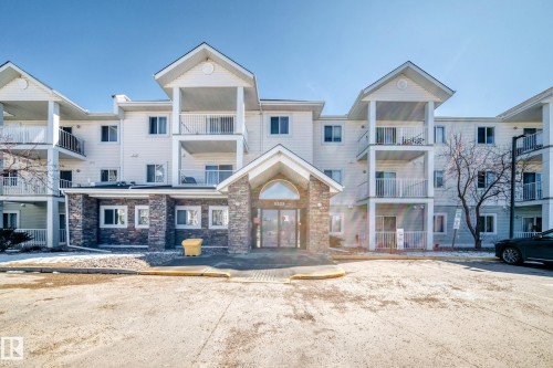 The property features a multi-story building with a stone facade on the ground level and light-colored siding on upper levels - 324 9525 162 Avenue Nw, Edmonton, AB - Outdoor With Facade