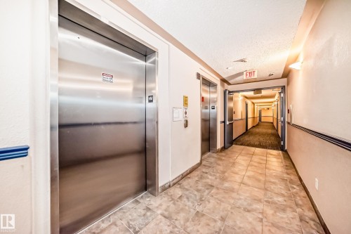 The building features two elevators with stainless steel doors, providing convenient access - 324 9525 162 Avenue Nw, Edmonton, AB - Indoor Photo Showing Other Room