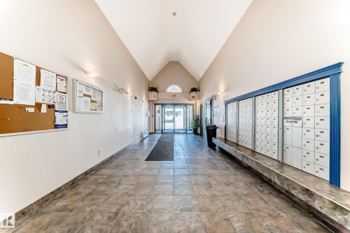 The property features a spacious entrance area with tiled flooring, a vaulted ceiling, and ample natural light from the glass entry doors - 324 9525 162 Avenue Nw, Edmonton, AB - Indoor Photo Showing Other Room
