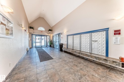 The property features a spacious common entry with tiled flooring, a vaulted ceiling, and wall-mounted lighting fixtures - 324 9525 162 Avenue Nw, Edmonton, AB - Indoor Photo Showing Other Room