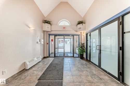 The property features a spacious entrance with tiled flooring, a vaulted ceiling, and glass doors providing natural light - 324 9525 162 Avenue Nw, Edmonton, AB - Indoor Photo Showing Other Room