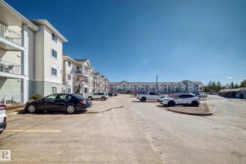 The property features a large parking area with paved surfaces, and a multi-level building with individual balconies - 324 9525 162 Avenue Nw, Edmonton, AB - Outdoor