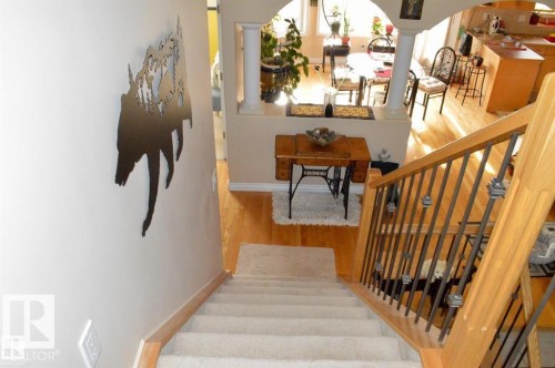 Carpeted staircase with light wood handrails and dark metal balusters, overlooking a living area with hardwood floors, a dining area, and kitchen - 16832 79 Street Nw, Edmonton, AB - Indoor Photo Showing Other Room