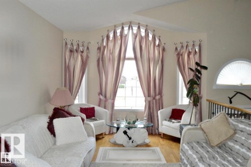 Living area featuring hardwood flooring, an arched window, and large windows with custom drapery - 16832 79 Street Nw, Edmonton, AB - Indoor Photo Showing Bedroom