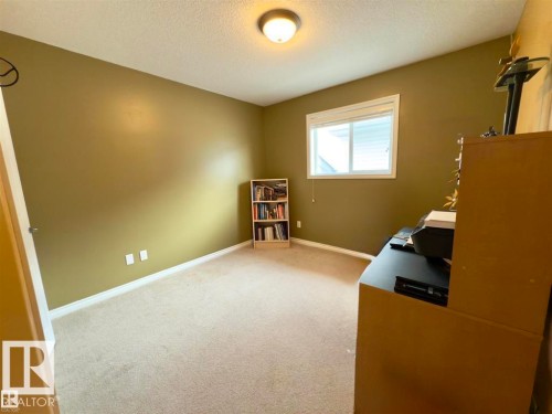 This room features wall-to-wall carpeting, a window providing natural light, and a ceiling light fixture - 16832 79 Street Nw, Edmonton, AB - Indoor