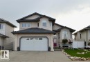 The property features a stucco exterior, a two-car garage with a concrete driveway, and a red front door - 16832 79 Street Nw, Edmonton, AB  - Outdoor With Facade 