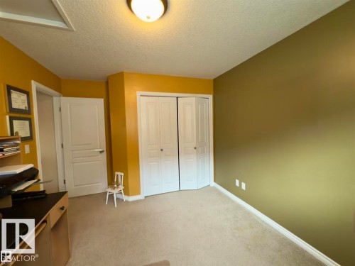 This room features carpeted flooring, a ceiling light fixture, and walls painted in two distinct colors - 16832 79 Street Nw, Edmonton, AB - Indoor Photo Showing Other Room