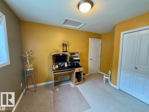 This versatile room features carpeted flooring, a light fixture, a window with white trim, and a built-in closet with white bifold doors - 16832 79 Street Nw, Edmonton, AB - Indoor Photo Showing Other Room
