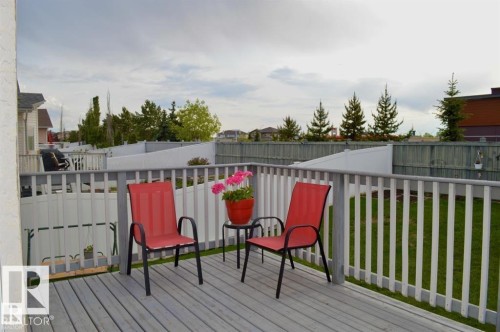 The property features a wooden deck with a white railing, overlooking a fenced yard with a lawn - 16832 79 Street Nw, Edmonton, AB - Outdoor With Deck Patio Veranda