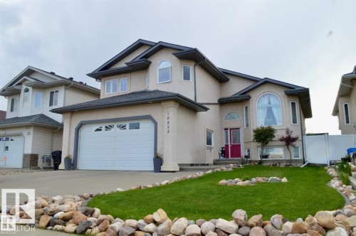 The property features a well-maintained lawn and a rock-bordered garden - 16832 79 Street Nw, Edmonton, AB - Outdoor With Facade