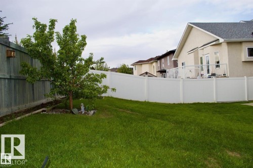 The property features a spacious yard with a well-maintained lawn, a mature tree, and privacy fencing - 16832 79 Street Nw, Edmonton, AB - Outdoor
