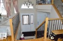 Entryway featuring a multi-level staircase with wrought iron balusters and wood handrails, a front door with an arched transom window, and tiled flooring - 16832 79 Street Nw, Edmonton, AB  - Indoor Photo Showing Other Room 